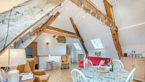 A cozy loft apartment with exposed wooden beams, a dining area with a floral tablecloth, and a red sofa. - 2 bedroom accommodation in Durham (Durham)