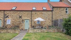 A stone building with a red-tiled roof, a green door, and a small patio area with a table and umbrella. - 2 bedroom accommodation in Durham (Durham)