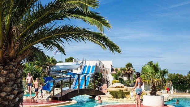 Ein Poolbereich mit Wasserrutsche und Palmen.