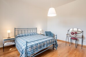 A bedroom with a bed, bedside tables, a chair, a desk, and a mirror.