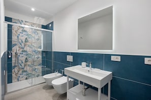 A modern bathroom with a glass shower enclosure, a white sink, and a bidet.