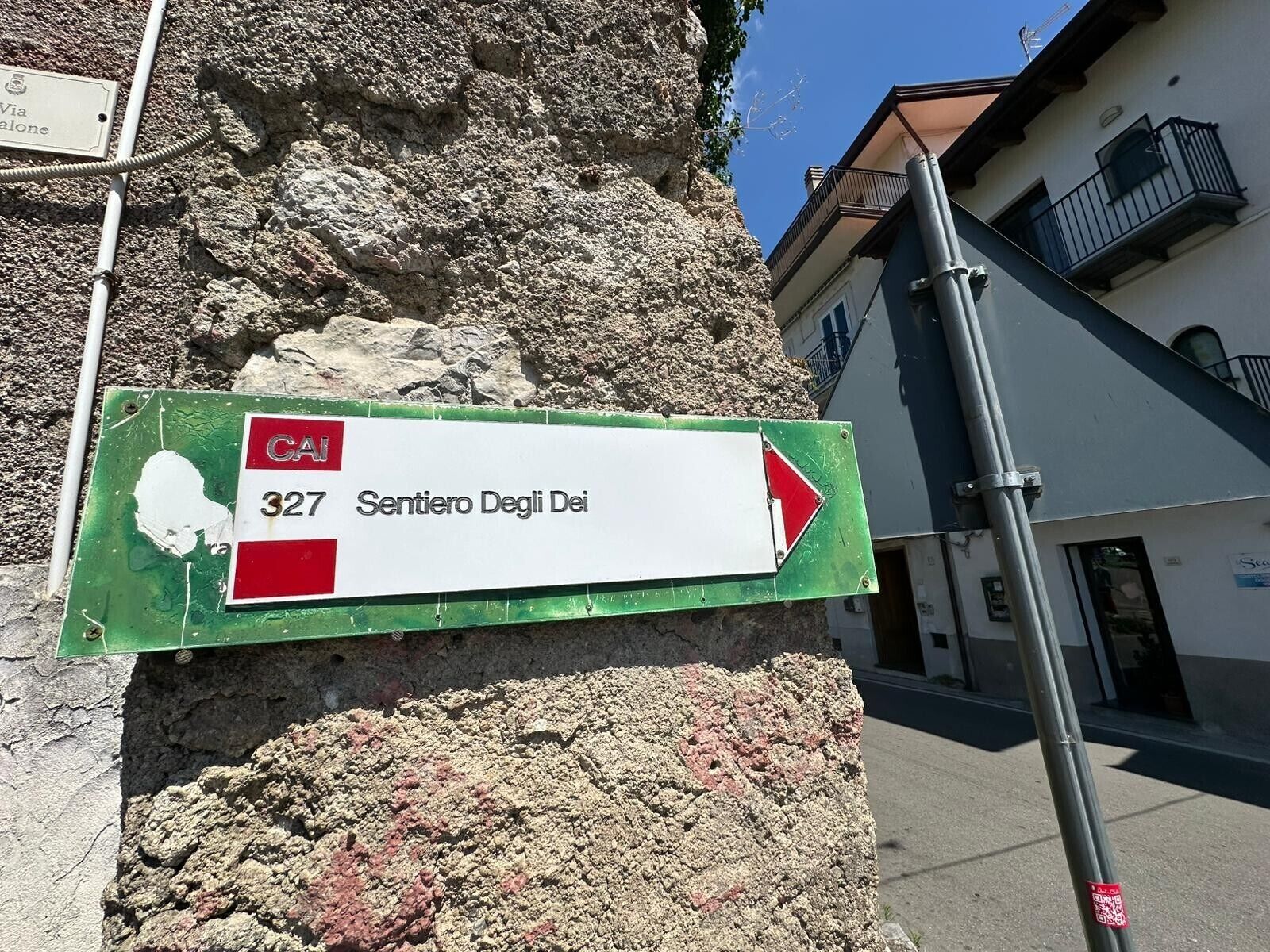 A street sign with '327 Sentiero Degli Dei' and a red arrow pointing right.