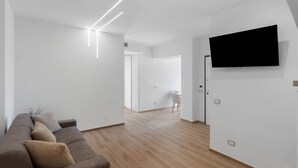 Un salon moderne avec un canapé, un téléviseur à écran plat fixé au mur et un plancher en bois.