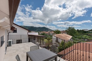 A balcony with a view of a mountainous landscape, a tiled floor, and outdoor furniture. - Suite Le Orchidee with Mountain View, Wi-Fi and Air Conditioning (Agerola)