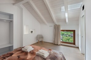 A bedroom with a bed, a chair, a window with curtains, and a view of greenery outside. - Suite Le Orchidee with Mountain View, Wi-Fi and Air Conditioning (Agerola)