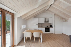Una cocina moderna con armarios blancos, una mesa de comedor de madera y un ventanal grande.