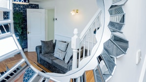 A modern living room with a grey sofa, a white door, and a spiral staircase.