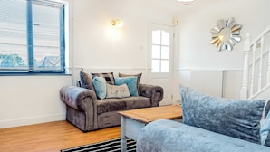 A living room with a grey sofa, a blue sofa, a wooden coffee table, and a black and white striped rug.