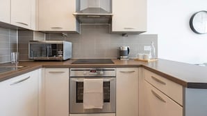 Een moderne keuken met roestvrijstalen apparatuur, waaronder een magnetron, koffiezetapparaat en oven.