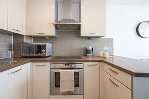 Una cocina moderna con electrodomésticos de acero inoxidable, incluyendo un microondas, cafetera y horno.
