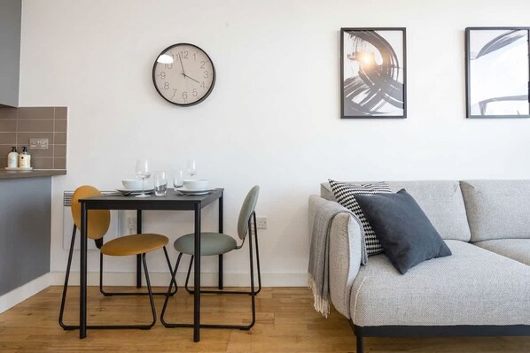 Un espacio habitable moderno con una mesa de comedor, sillas, un sofá, un reloj de pared y arte abstracto.