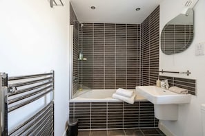 Une salle de bain avec une baignoire, un lavabo, un miroir et une douche.
