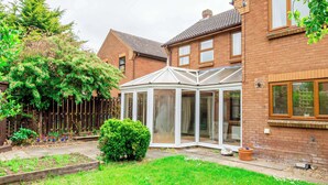 A brick house with a conservatory, a fenced garden, and a well-maintained lawn.