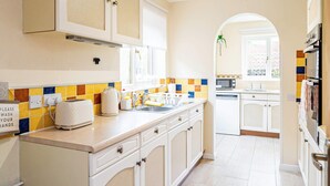 A kitchen with white cabinets, a tiled backsplash, a toaster, a sink, and a window with a view of buildings outside.