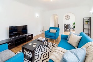En moderne stue med TV, blå sofa og et mønstret tæppe.
