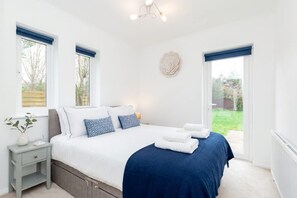 Een slaapkamer met een bed, nachtkastje en uitzicht op het omliggende landschap.