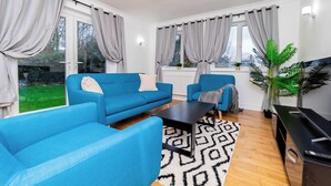 Un salon moderne avec un canapé bleu, une table basse noire et un téléviseur.