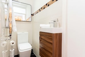 Een badkamer met een toilet, een wastafel met spiegel en een handdoekrek.