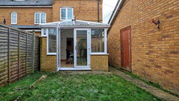 A brick house with a glass conservatory and a wooden fence.