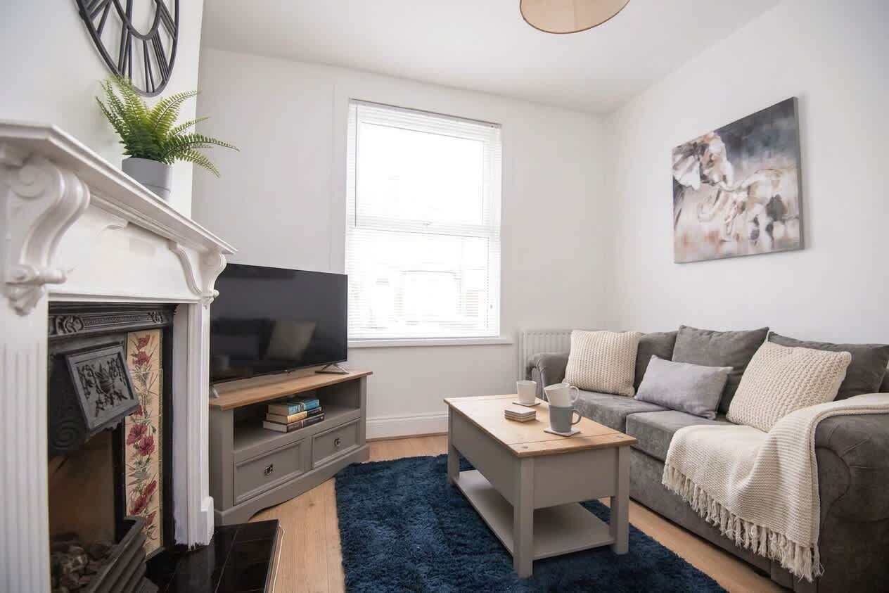 A living room with a fireplace, a television, a sofa, a coffee table, and a large window.
