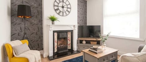 A living room with a fireplace, a clock, a television, and a sofa.