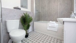 A modern bathroom with a toilet, shower, and sink. - Modern 3BR Home with Free Parking & Fast Wi-Fi (Rugby)