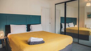 Ein Hotelzimmer mit einem großen Bett, einem Spiegel und einer Tür.
