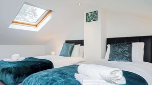 Une chambre d’hôtel avec deux lits, une lucarne, une œuvre d’art accrochée au mur et des serviettes soigneusement pliées sur les lits.