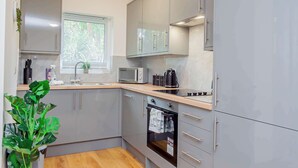 Une cuisine moderne avec des meubles gris, un four à micro-ondes, un four traditionnel et un évier.