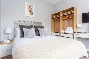A hotel room with a bed, a wardrobe, a desk, and a television.