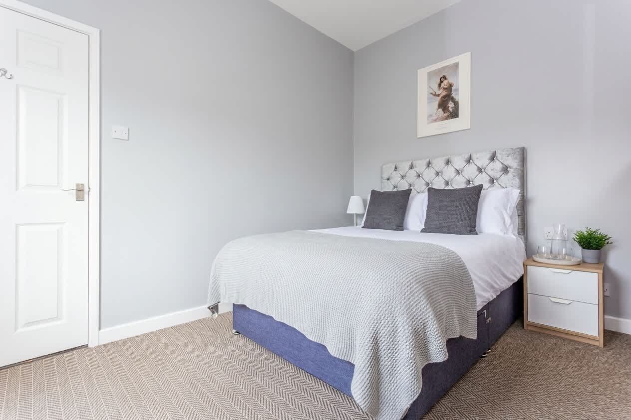 A bedroom with a bed, bedside table, and a wall-mounted picture.