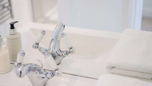A bathroom with a chrome faucet, a soap dispenser, and a folded white towel.