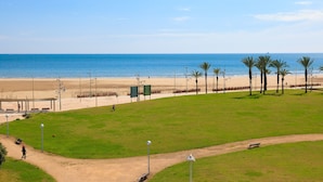 A beach with a grassy area, benches, and a path leading to the beach. - Mar Internum: Family Apartment in La Pineda (La Pineda)