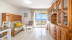 A spacious living room with a sofa, chairs, a dining table, and wooden cabinets. - Mar Internum: Family Apartment in La Pineda (La Pineda)
