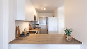 A narrow kitchen with white walls, a wooden countertop, and a stainless steel refrigerator. - Ground floor flat on the beachfront in Cambrils - 249 UHC DMS V (Cambrils)
