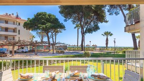 A dining area with tables set for two, overlooking a street with parked cars and trees. - Ground floor flat on the beachfront in Cambrils - 249 UHC DMS V (Cambrils)