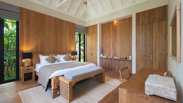 Un dormitorio espacioso con una cama grande, paneles de madera, un banco de madera y una mesita con un banco.