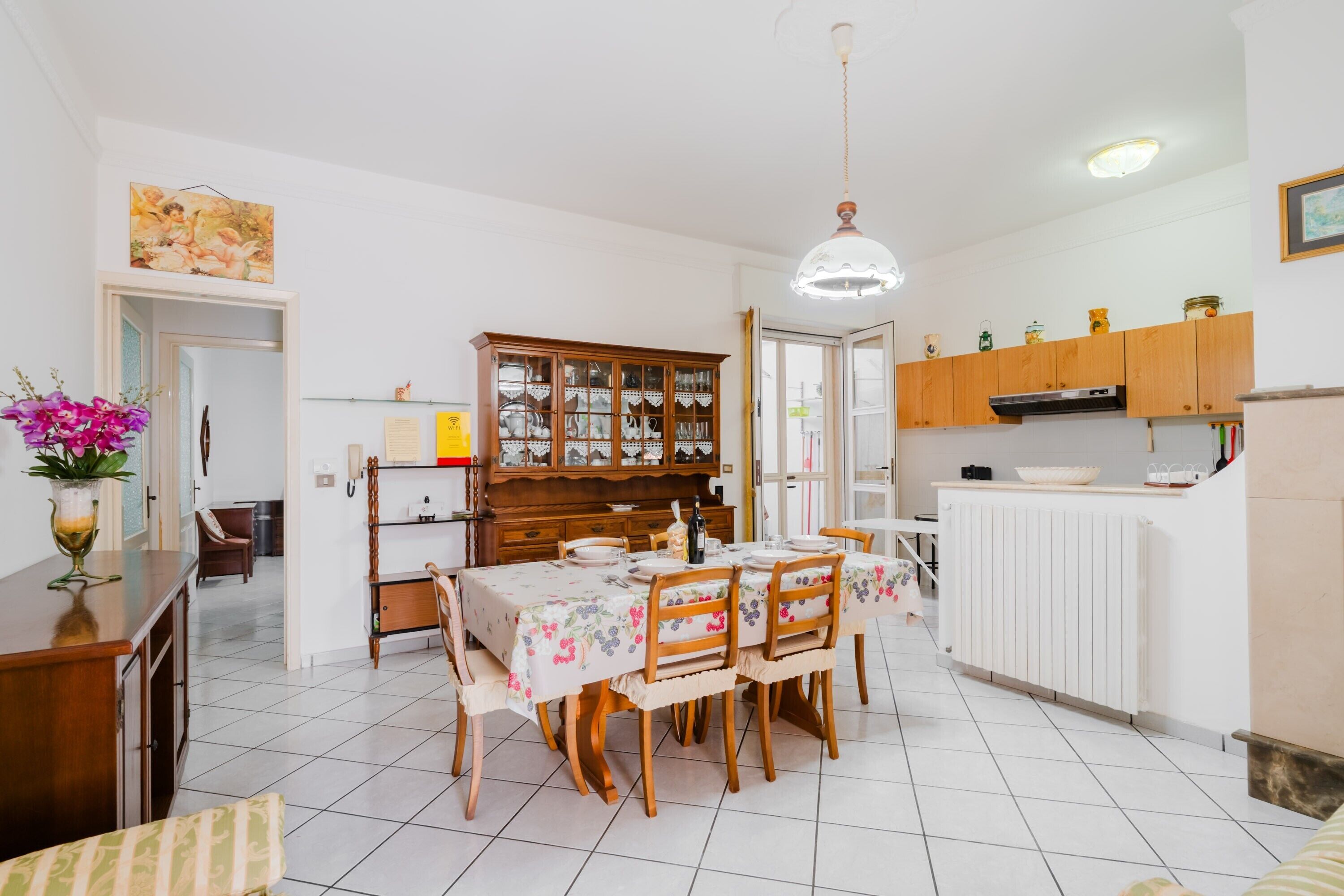 A dining area with a table set for four, a wooden cabinet with glass doors, and a white radiator.