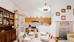 A dining area with a table set for four, wooden cabinets, a kitchen in the background, and a fireplace. - Holiday Home 'Simona' with Shared Terrace, Wi-Fi and Air Conditioning (Taviano)