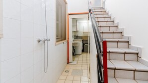 A narrow hallway with a shower, a staircase with beige steps, and a small kitchen area visible through an open door. - Holiday Home 'Simona' with Shared Terrace, Wi-Fi and Air Conditioning (Taviano)