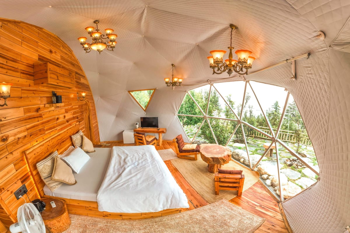 A cozy, wooden-themed bedroom with a bed, seating area, and a TV.