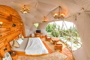 A cozy, wooden-themed bedroom with a bed, seating area, and a TV. - Glamoreo (Theog)
