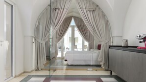 A modern hotel room with a large bed, a desk, and a view through a glass door. - Hydeout Palace - Luxury & Spa Suites by Wonderful Italy (San Vito dei Normanni)