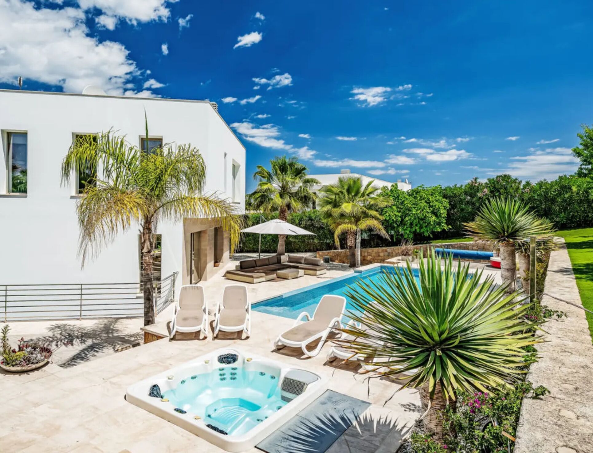 Ein modernes Haus mit Swimmingpool, Sitzgelegenheit im Freien und Whirlpool.