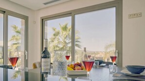 A room with large windows, a glass table, and a bowl of fruit. - VILLA EOS luxury villa in a quiet location (Xàbia)