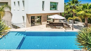 A modern two-story house with a swimming pool, outdoor seating, and palm trees. - VILLA EOS luxury villa in a quiet location (Xàbia)