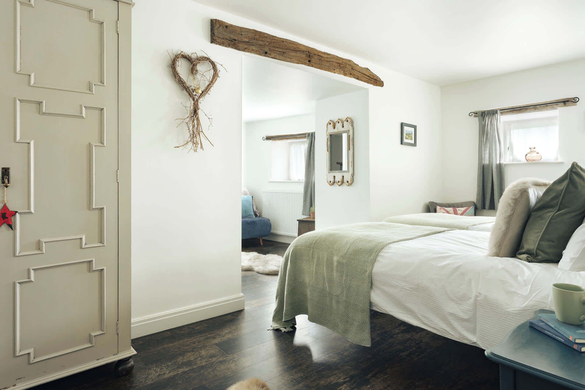Un dormitorio con una cama grande, un aparador, un espejo y una decoración con forma de corazón en la pared.