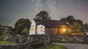 A stone house with a sloped roof, a stone wall, and a grassy area in front. - Jackson's Barn | Ridgestone (Water Yeat)