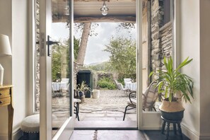 A doorway leading to an outdoor patio with stone flooring, a table, chairs, and a potted plant. - Jackson's Barn | Ridgestone (Water Yeat)