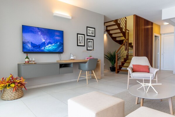 Una sala de estar moderna con un televisor de pantalla plana, una escalera de madera y un comedor.